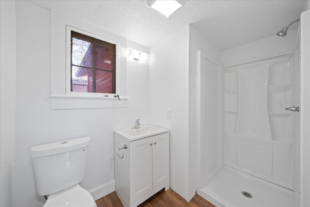 bathroom with hardwood / wood-style floors, a shower, vanity, toilet, and a textured ceiling