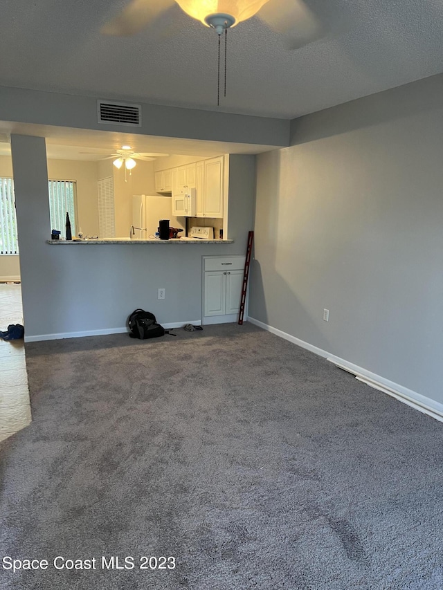 unfurnished living room with ceiling fan, carpet flooring, and a textured ceiling