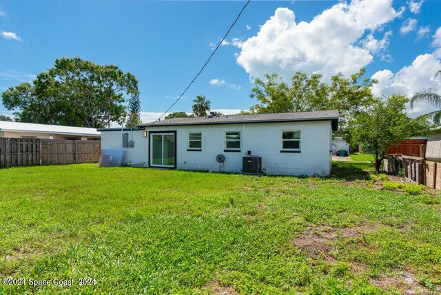 rear view of property with a yard and cooling unit