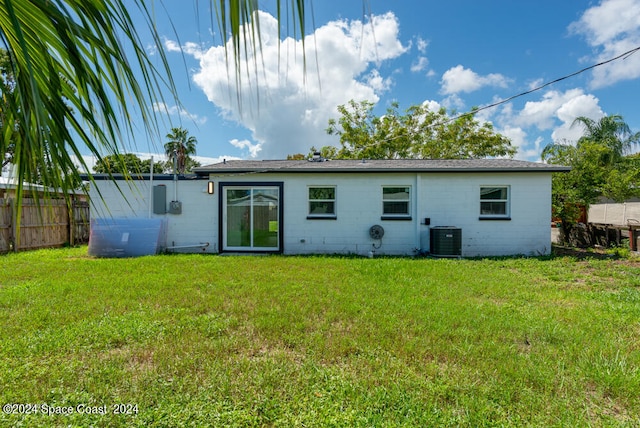 back of property featuring cooling unit and a lawn