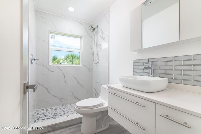 bathroom featuring vanity, tiled shower, backsplash, and toilet