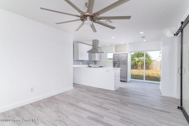 kitchen featuring tasteful backsplash, white cabinetry, island exhaust hood, stainless steel refrigerator with ice dispenser, and a barn door