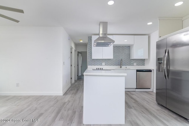 kitchen with sink, island range hood, stainless steel appliances, decorative backsplash, and white cabinets