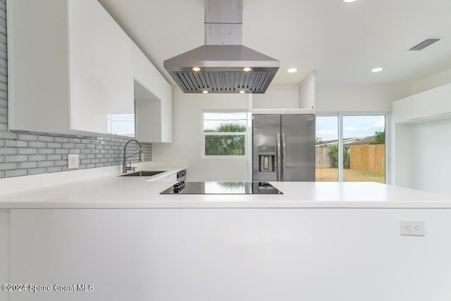 kitchen featuring sink, black electric stovetop, white cabinets, island exhaust hood, and stainless steel fridge with ice dispenser