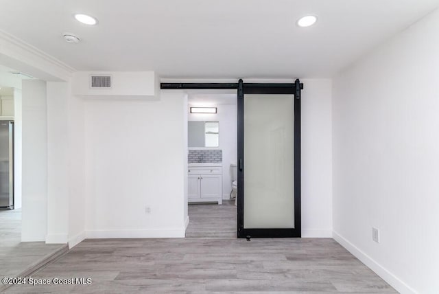 spare room featuring a barn door and light wood-type flooring