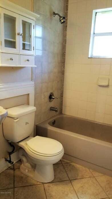 bathroom with tiled shower / bath, tile patterned floors, and toilet