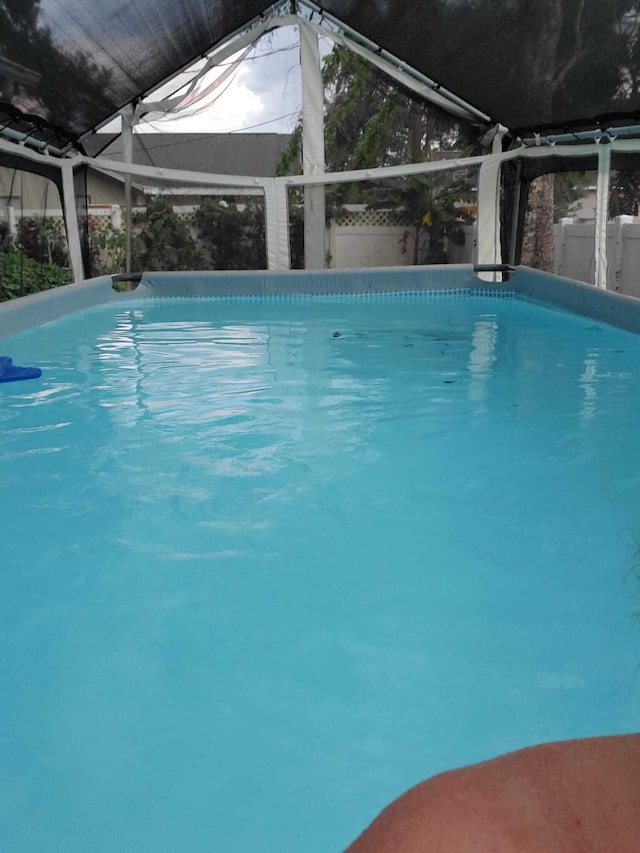 view of swimming pool featuring glass enclosure