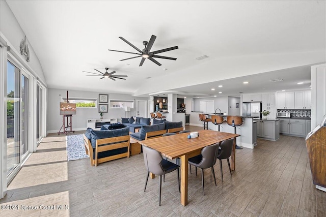 dining room featuring vaulted ceiling, light hardwood / wood-style flooring, and sink