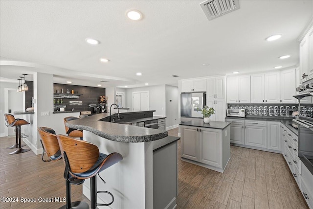 kitchen with white cabinets, a center island, stainless steel refrigerator, and light hardwood / wood-style flooring