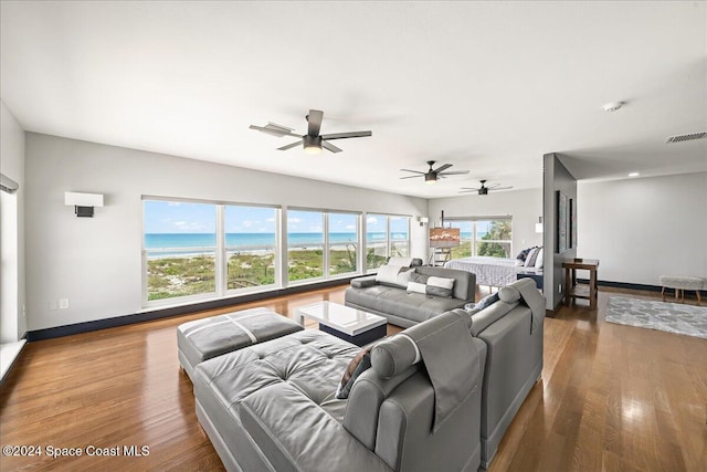 living room featuring hardwood / wood-style floors, a water view, and ceiling fan