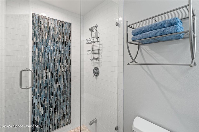 bathroom featuring toilet and a shower with shower door