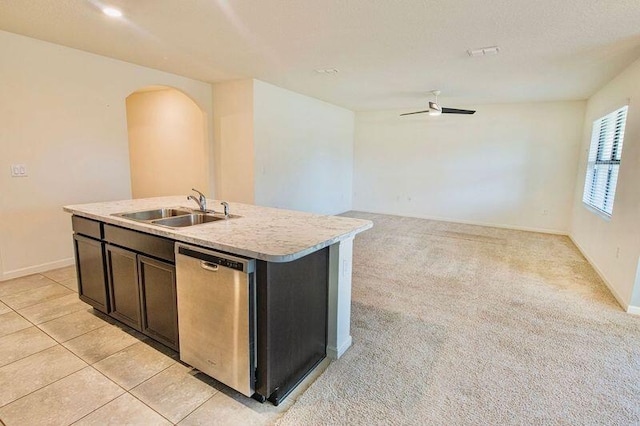 kitchen featuring sink, light tile patterned floors, dishwasher, ceiling fan, and an island with sink