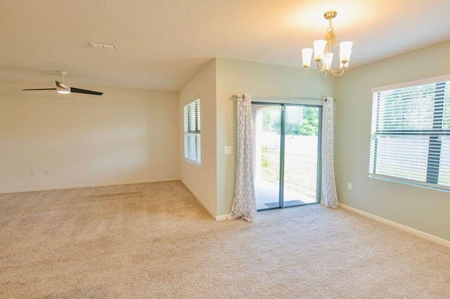 carpeted spare room with ceiling fan with notable chandelier and a textured ceiling