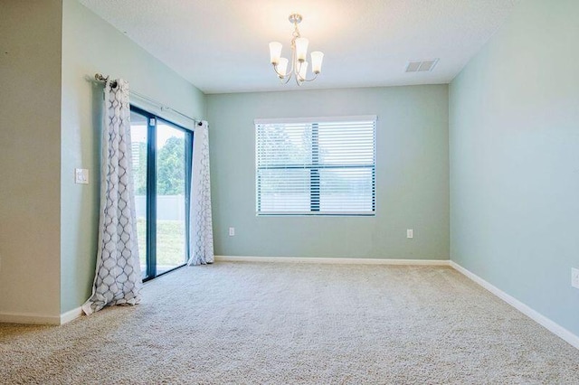 spare room featuring light carpet and a notable chandelier