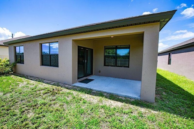 back of property featuring a patio and a lawn