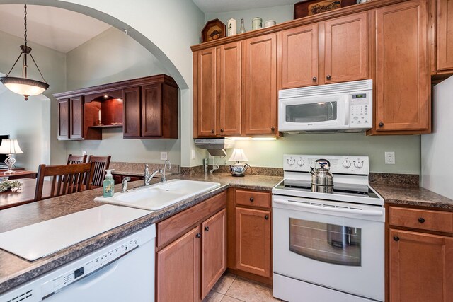 kitchen featuring light tile patterned floors, hanging light fixtures, white appliances, and sink