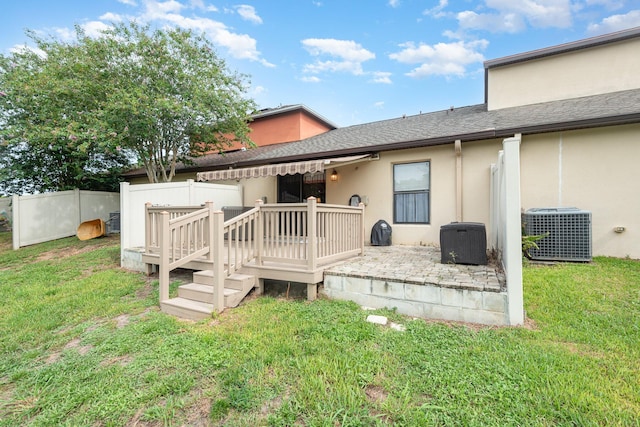 rear view of house with a wooden deck, central AC unit, and a lawn