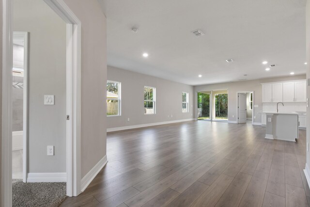 unfurnished living room featuring light hardwood / wood-style floors, sink, and plenty of natural light