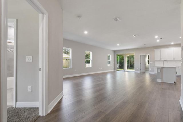 unfurnished living room featuring wood-type flooring and sink