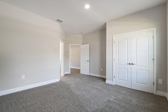 unfurnished bedroom with a closet and dark colored carpet