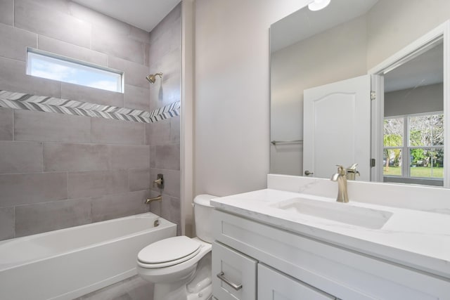 full bathroom featuring tiled shower / bath, vanity, and toilet