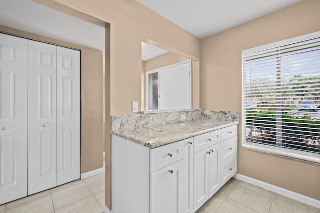 kitchen with light tile patterned flooring, light stone countertops, and white cabinets