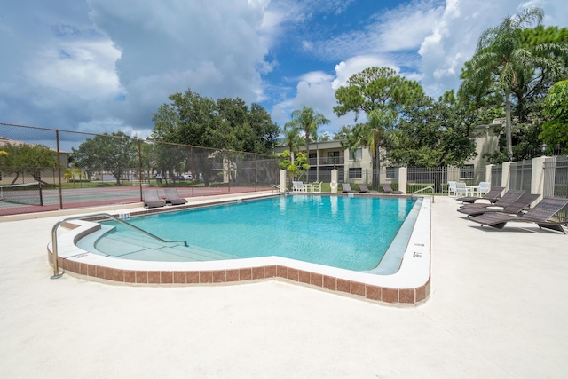 view of swimming pool featuring tennis court