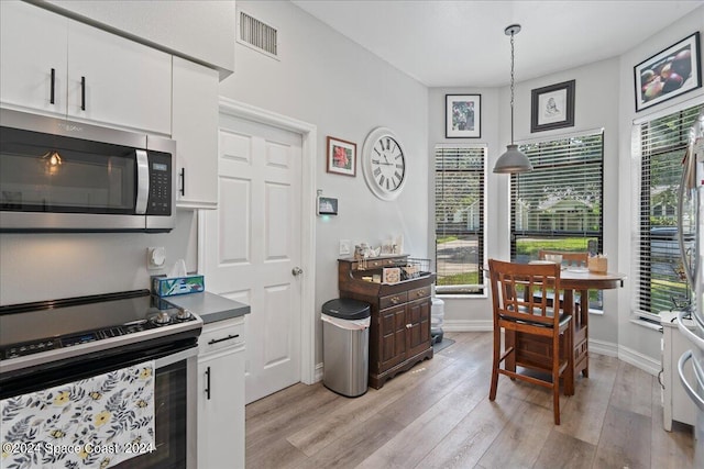 kitchen featuring white cabinets, light wood-type flooring, range with electric stovetop, and pendant lighting