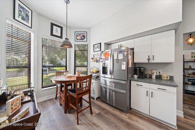 kitchen with hardwood / wood-style floors, stainless steel refrigerator with ice dispenser, white cabinetry, and decorative light fixtures