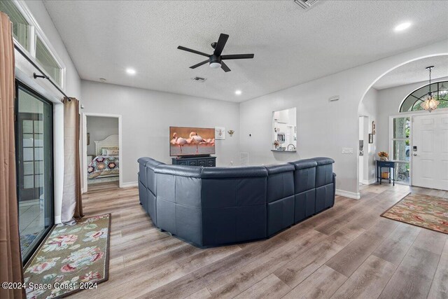 living room with ceiling fan, light hardwood / wood-style flooring, and a textured ceiling