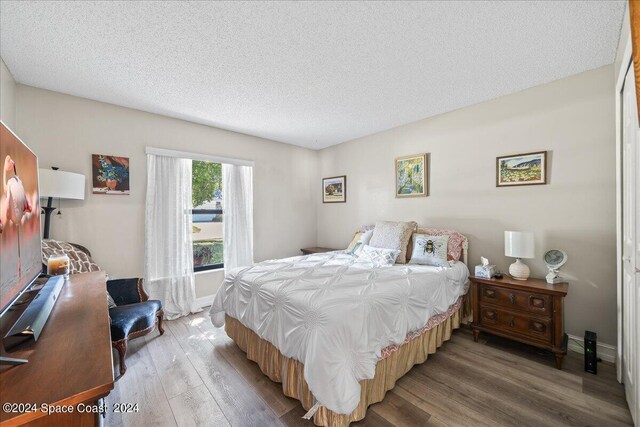 bedroom with a textured ceiling and wood-type flooring