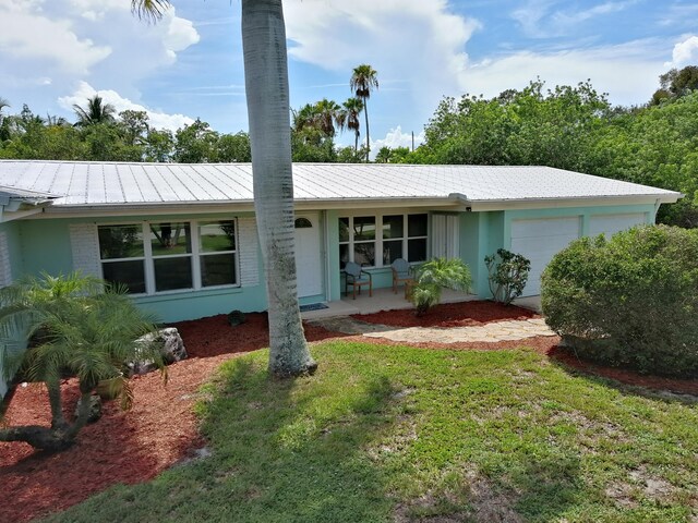 ranch-style home with a garage, a front lawn, and a porch