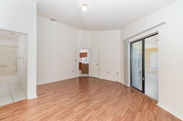 unfurnished room with light hardwood / wood-style flooring and a textured ceiling