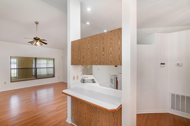 kitchen featuring white range with electric cooktop, sink, light hardwood / wood-style flooring, kitchen peninsula, and ceiling fan