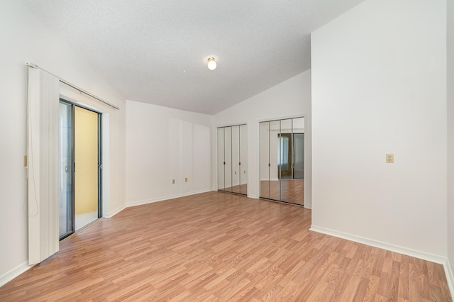 unfurnished room with lofted ceiling, light hardwood / wood-style floors, and a textured ceiling