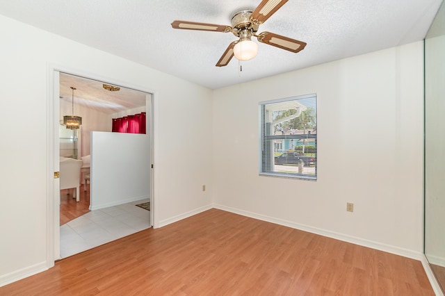 spare room with ceiling fan, a textured ceiling, and light wood-type flooring