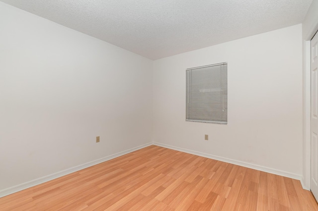 unfurnished room featuring light hardwood / wood-style flooring and a textured ceiling