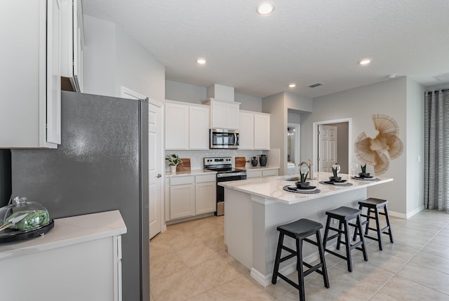 kitchen featuring appliances with stainless steel finishes, sink, white cabinets, a breakfast bar area, and an island with sink