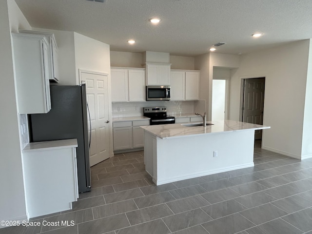 kitchen with sink, white cabinetry, appliances with stainless steel finishes, an island with sink, and decorative backsplash