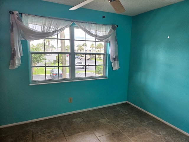 tiled spare room with plenty of natural light, a textured ceiling, and ceiling fan