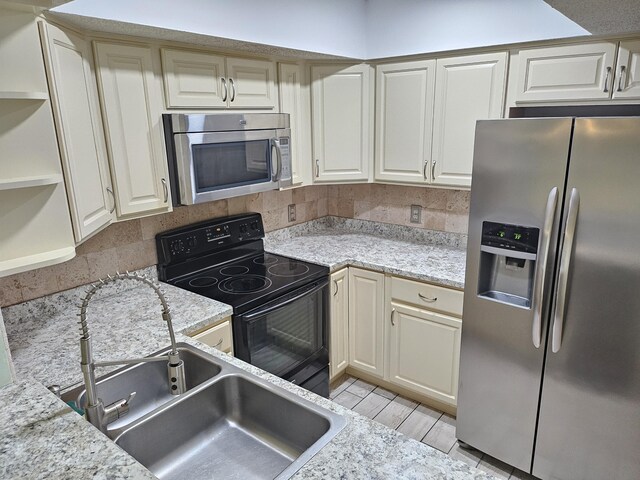 kitchen featuring cream cabinets, light stone countertops, and appliances with stainless steel finishes