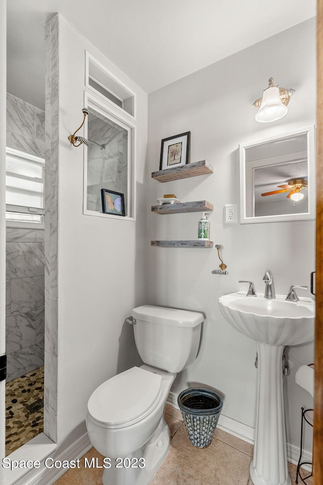 bathroom with a tile shower, toilet, and tile patterned floors