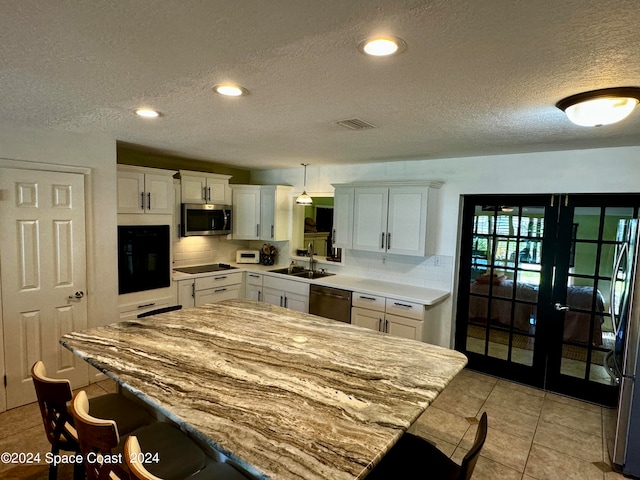 kitchen featuring pendant lighting, a textured ceiling, white cabinetry, and black appliances