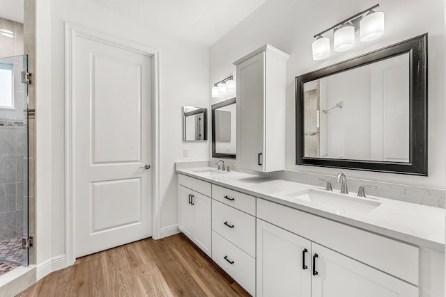 bathroom with tiled shower, hardwood / wood-style flooring, and dual bowl vanity