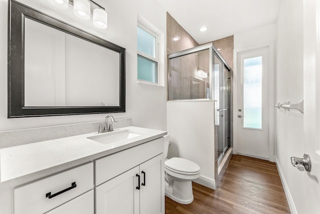 bathroom with a shower with shower door, vanity, hardwood / wood-style floors, and toilet