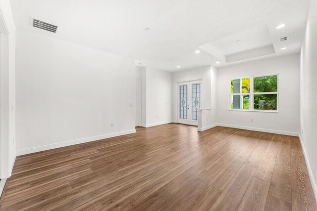 spare room with hardwood / wood-style flooring, a raised ceiling, and french doors