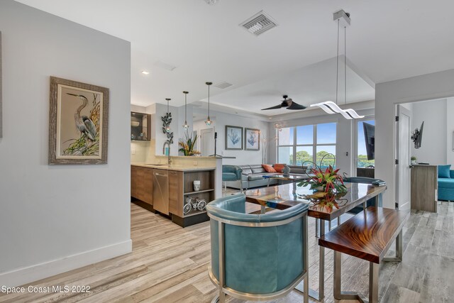 kitchen featuring light wood-type flooring, dishwasher, ceiling fan, decorative light fixtures, and sink