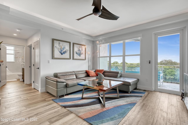 living room featuring baseboards, light wood-style floors, and ceiling fan
