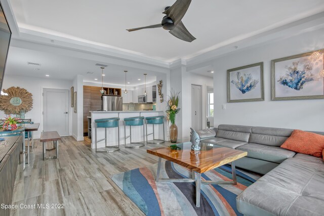 living room with ceiling fan, sink, and light hardwood / wood-style flooring