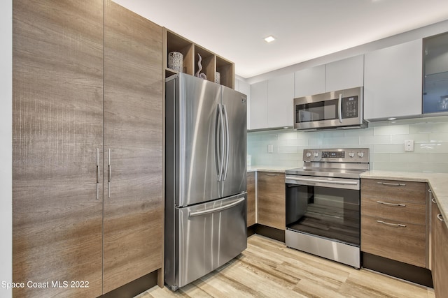 kitchen featuring light countertops, stainless steel appliances, backsplash, and light wood-type flooring